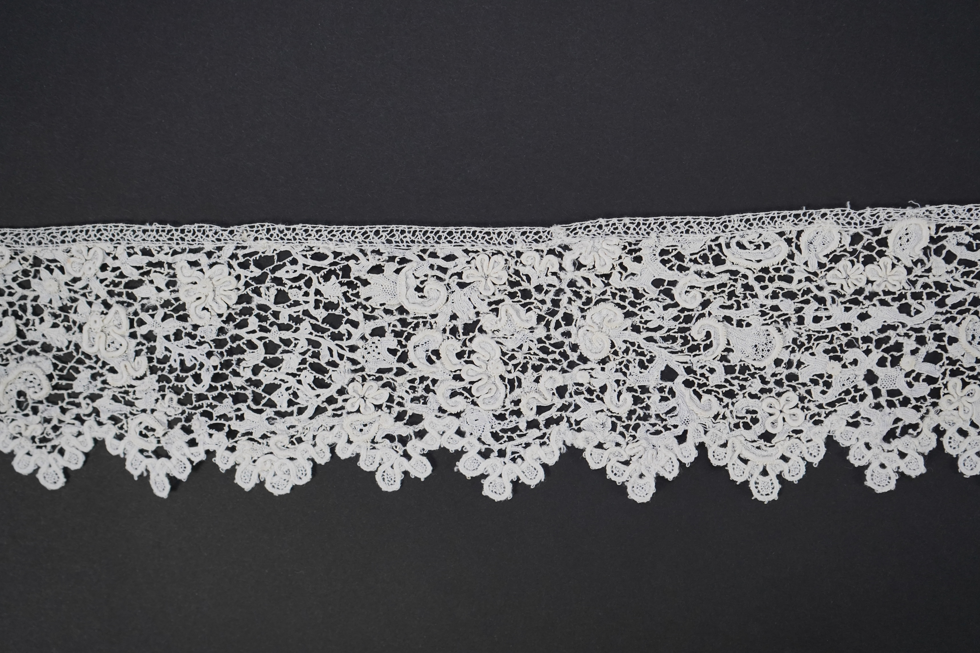 A late 17th century wide flounce of Point de France needle lace, together with a narrower flounce, both with raised elements of the design in the style of Point de Rose, but less so. This lace was very popular with the F